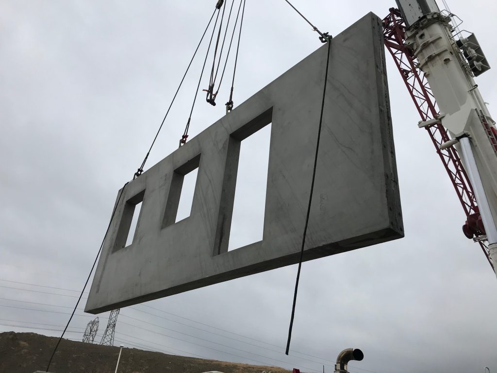 concrete wall being lifted into place by crane
